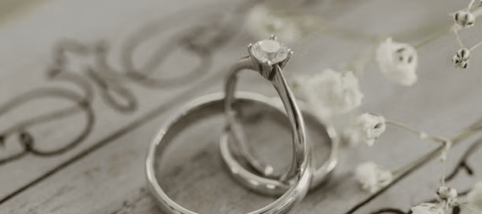 Two wedding bands resting on a mirror beside baby’s breath